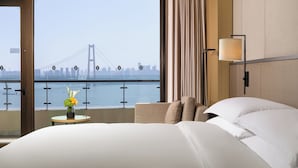 Une chambre d’hôtel dotée d’une grande fenêtre donnant sur un pont et sur le panorama de la ville.