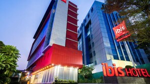 Un hotel con una fachada destacada en rojo y azul, un cartel grande de 'ibis' y un letrero que indica 'ENTRY', señalando la entrada.