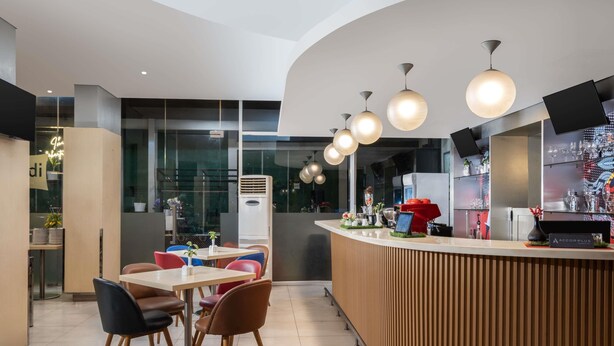 Un interior de restaurante moderno con una barra curva, varias mesas y sillas.