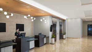 Una zona de recepción moderna con recepcionista, techo de madera y suelo de mármol.