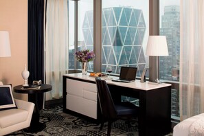 Habitación de hotel con escritorio, silla y vista a un edificio moderno.