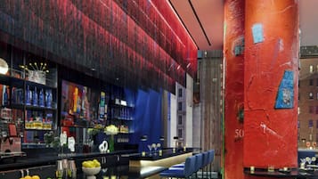 A modern bar area with a counter, stools, and a vibrant red wall.