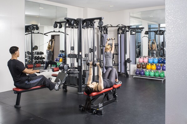 Un gimnasio con equipo de ejercicio, una banca y pesas de kettlebell.