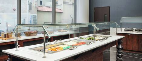 A buffet setup with various food items and a glass display case.