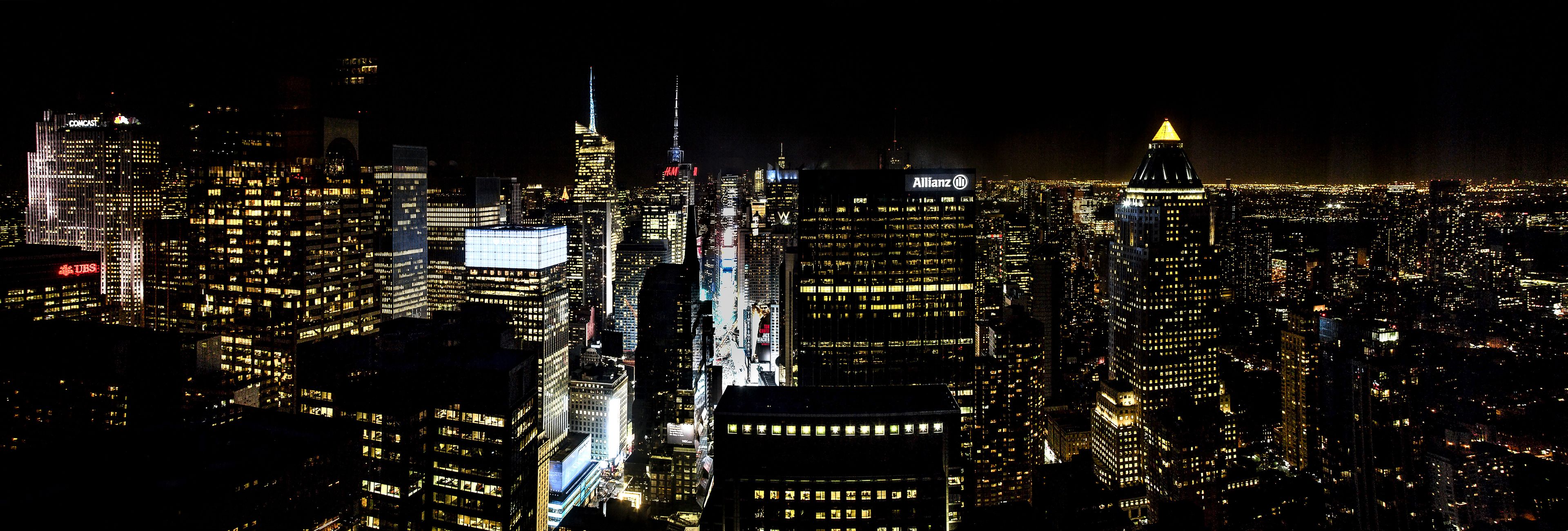 A nighttime cityscape with illuminated skyscrapers and a prominent building with a lit dome.