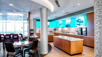 En moderne hotellobby med en central ø, siddeområde og en køkkenbar.