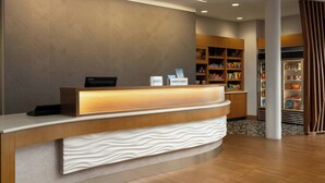 Een hotel receptie met een modern design, met een receptiebalie, een patroonmuur en een goed gevulde minibar.