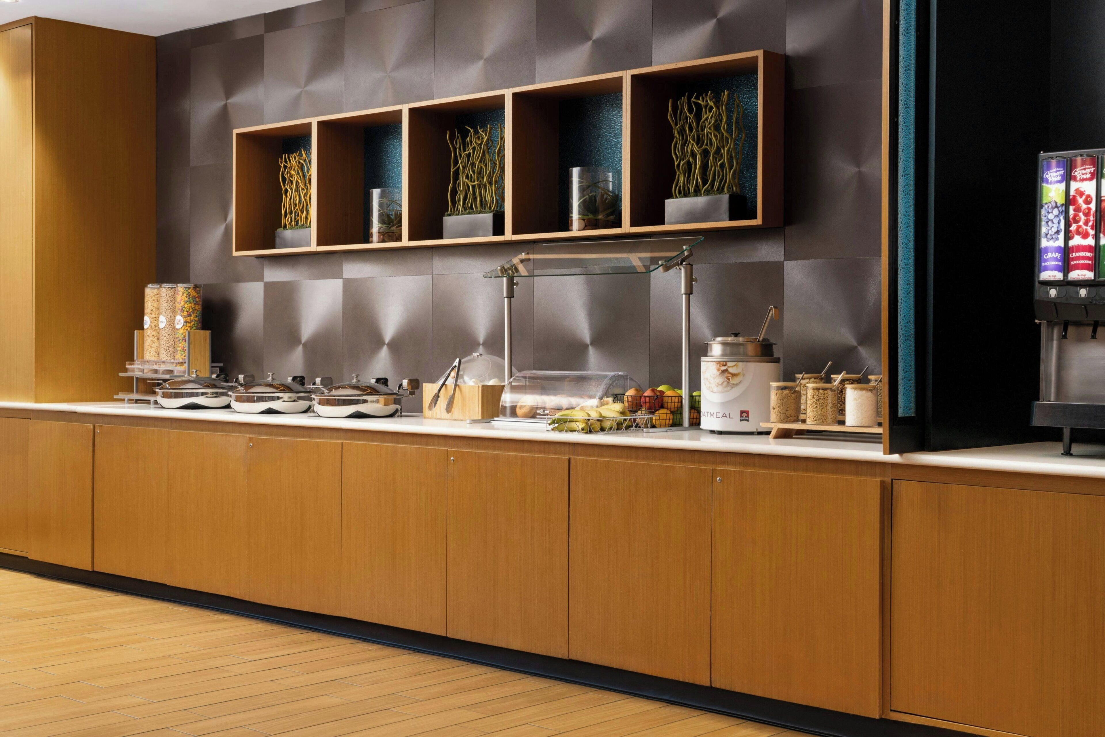 Un'area reception di un hotel moderno con un bancone in legno, una teca in vetro e una macchina per il caffè.