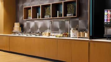 Un'area reception di un hotel moderno con un bancone in legno, una teca in vetro e una macchina per il caffè.