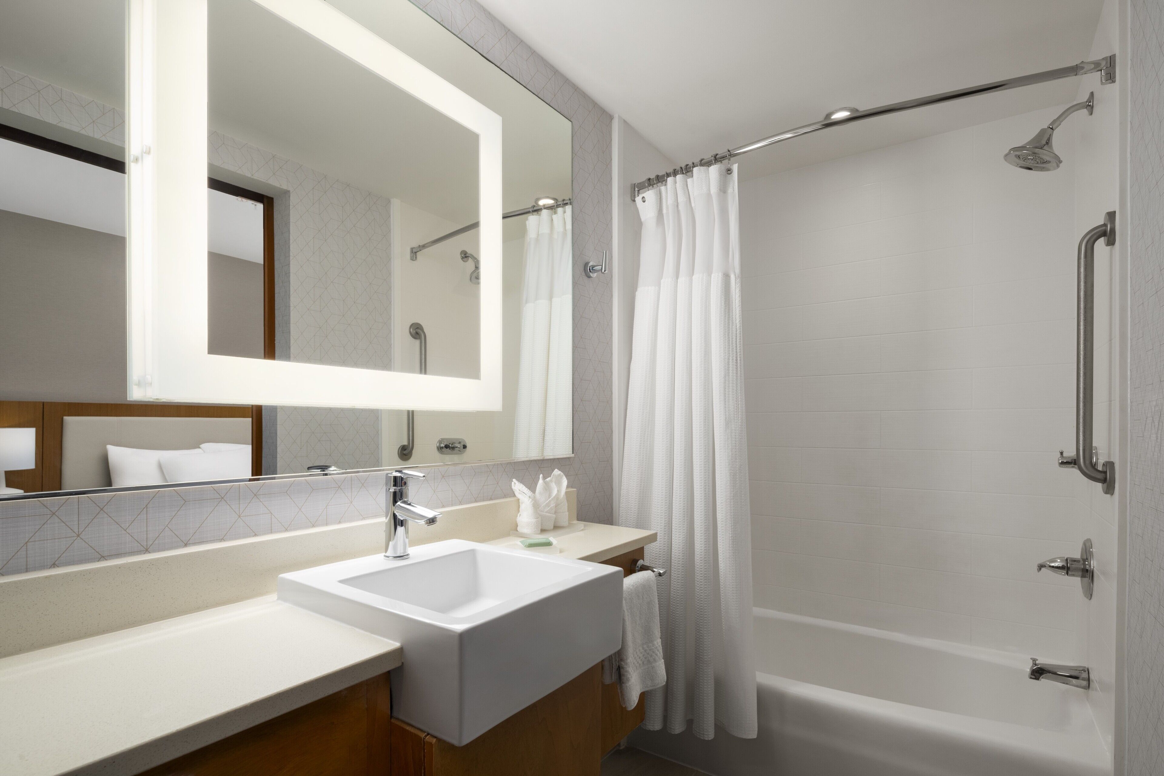 Une salle de bain moderne avec un grand miroir, un lavabo, une baignoire et une douche.