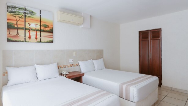 Ein Hotelzimmer mit zwei Betten, einem Holzschrank, einer Wand-Klimaanlage und einem Gemälde, das einen Sonnenuntergang über einer Savanne zeigt.