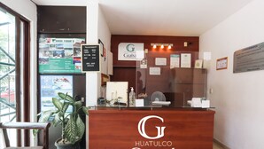 Eine Rezeption mit Holzoptik und dem Logo "Huatulco Guivá".