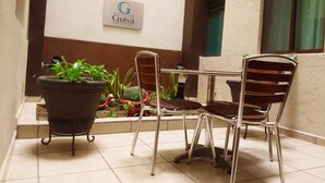 Eine Terrasse mit Tisch und Stühlen, Topfpflanzen und einem Schild für das Hotel Huatuco Guivá.