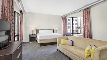 Een hotelkamer met een bed, een bank, een televisie en een bureau.