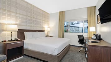 A hotel room with a large bed, bedside tables with lamps, a desk with a chair, and a TV mounted on the wall.