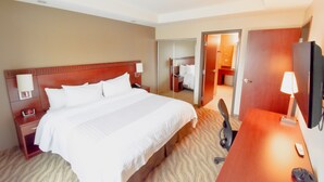 A hotel room with a large bed, bedside tables, a desk, and a TV. - Canad Inns Destination Centre Garden City (Winnipeg)