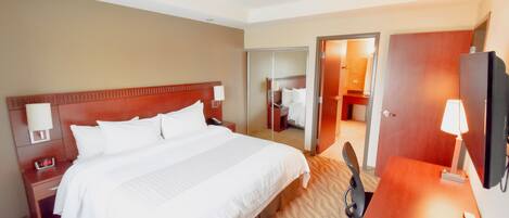 A hotel room with a large bed, bedside tables, a desk, and a TV.