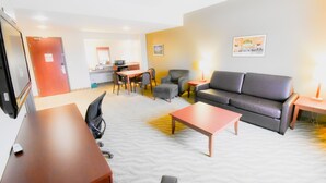 A hotel room with a sofa, armchair, coffee table, desk, and a television. - Canad Inns Destination Centre Garden City (Winnipeg)