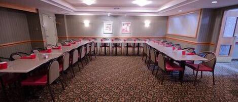 A conference room with a carpeted floor, long tables, and chairs.