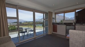 Una cocina moderna con ventanas amplias, un comedor con sillas y vistas a montañas y un lago.