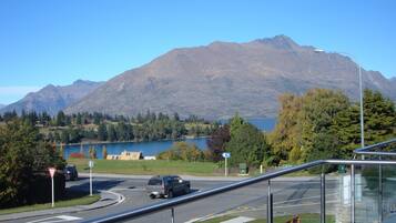 Una carretera con una montaña al fondo, un lago y una senda peatonal.