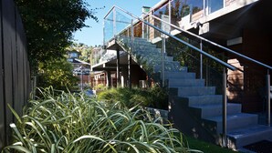Un edificio moderno con una escalera de cristal, un piso de hormigón y un exuberante jardín verde.