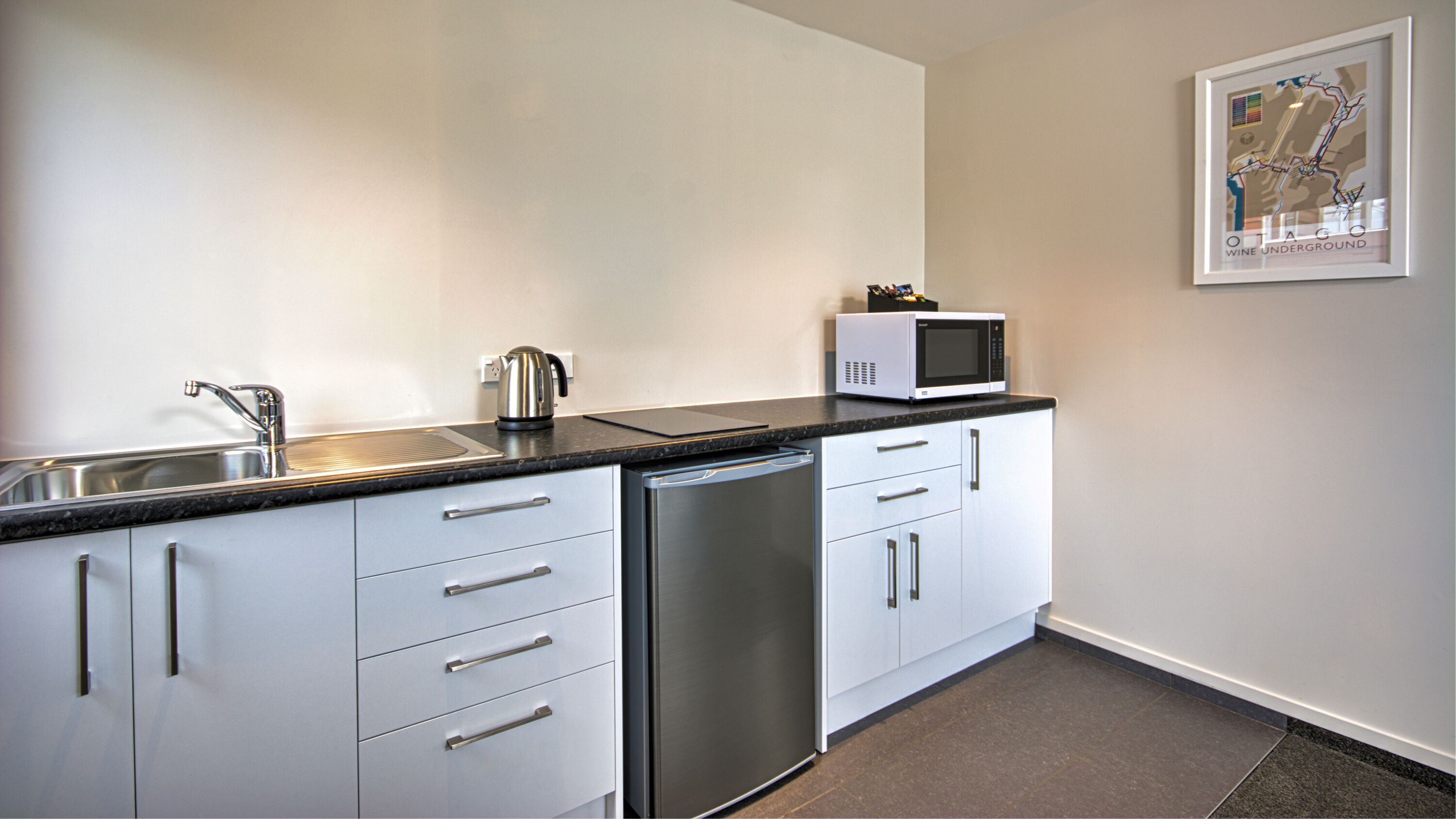 Een moderne keuken met een vaatwasser, een magnetron en een waterkoker.