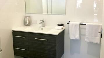 Een moderne badkamer met een wit wastafel, donkere wastafelmeubel en een grote spiegel.