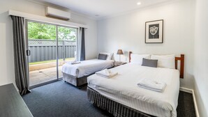 Hotelkamer met twee bedden, een grote schuifpui naar buiten en een lijst met een afbeelding aan de muur.
