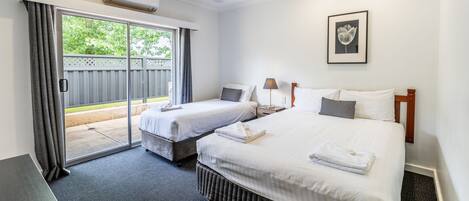 Ein Hotelzimmer mit zwei Betten, einer großen Schiebetür nach draußen und einem gerahmten Bild an der Wand.