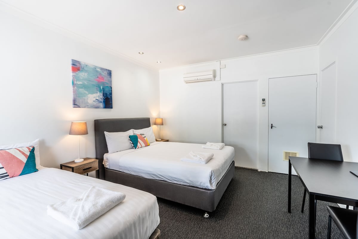 Une chambre d’hôtel avec deux lits, un bureau et une porte.