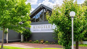 Kingsley Motel & Restaurant met een modern design, herkenbaar aan een opvallend bord, een verharde oprit en weelderige begroeiing.