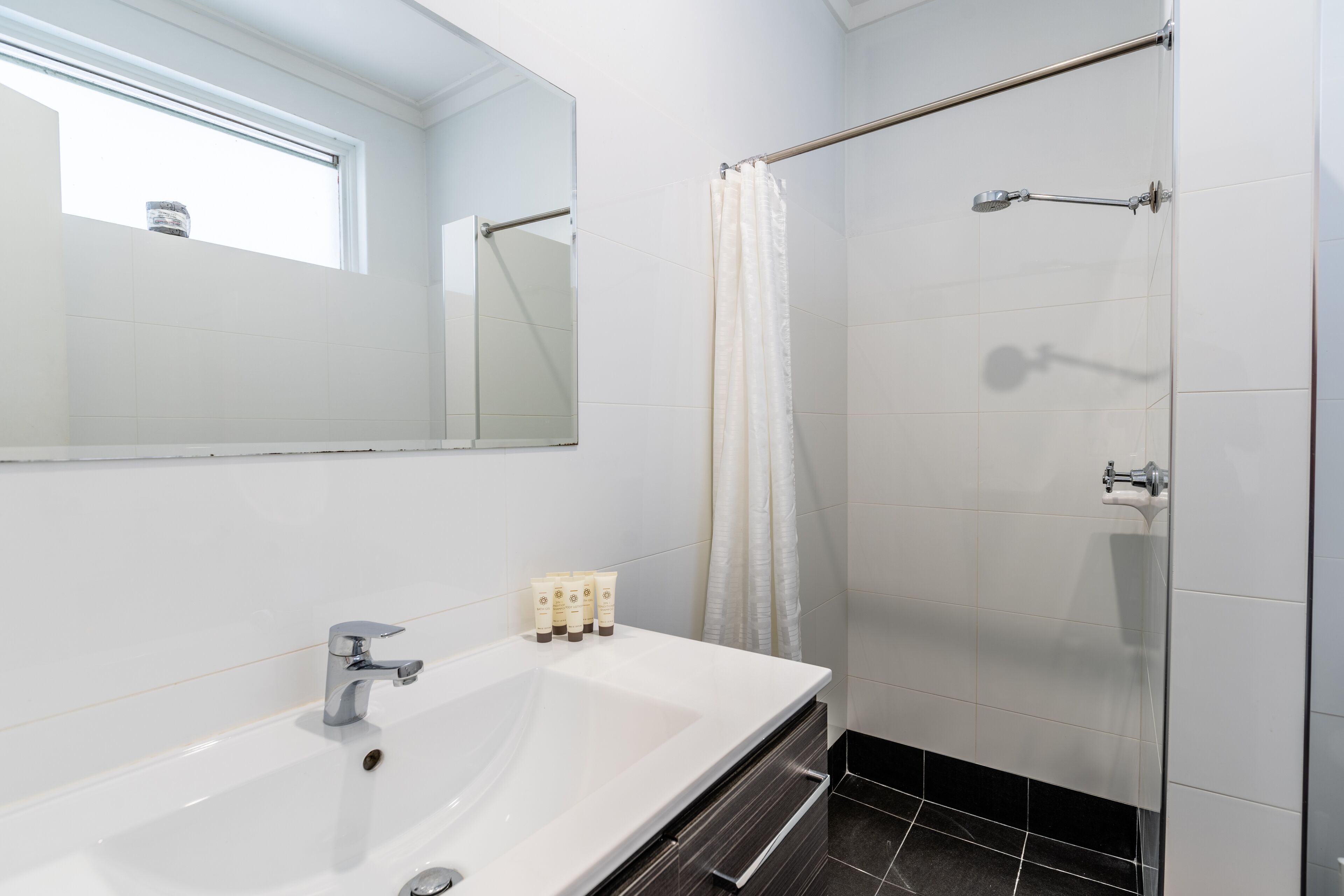 Un baño moderno con un lavamanos grande, una ducha con puerta de vidrio y un espejo sobre el lavamanos.