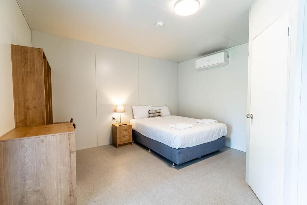 Un dormitorio con cama, mesita de noche y un armario de madera.