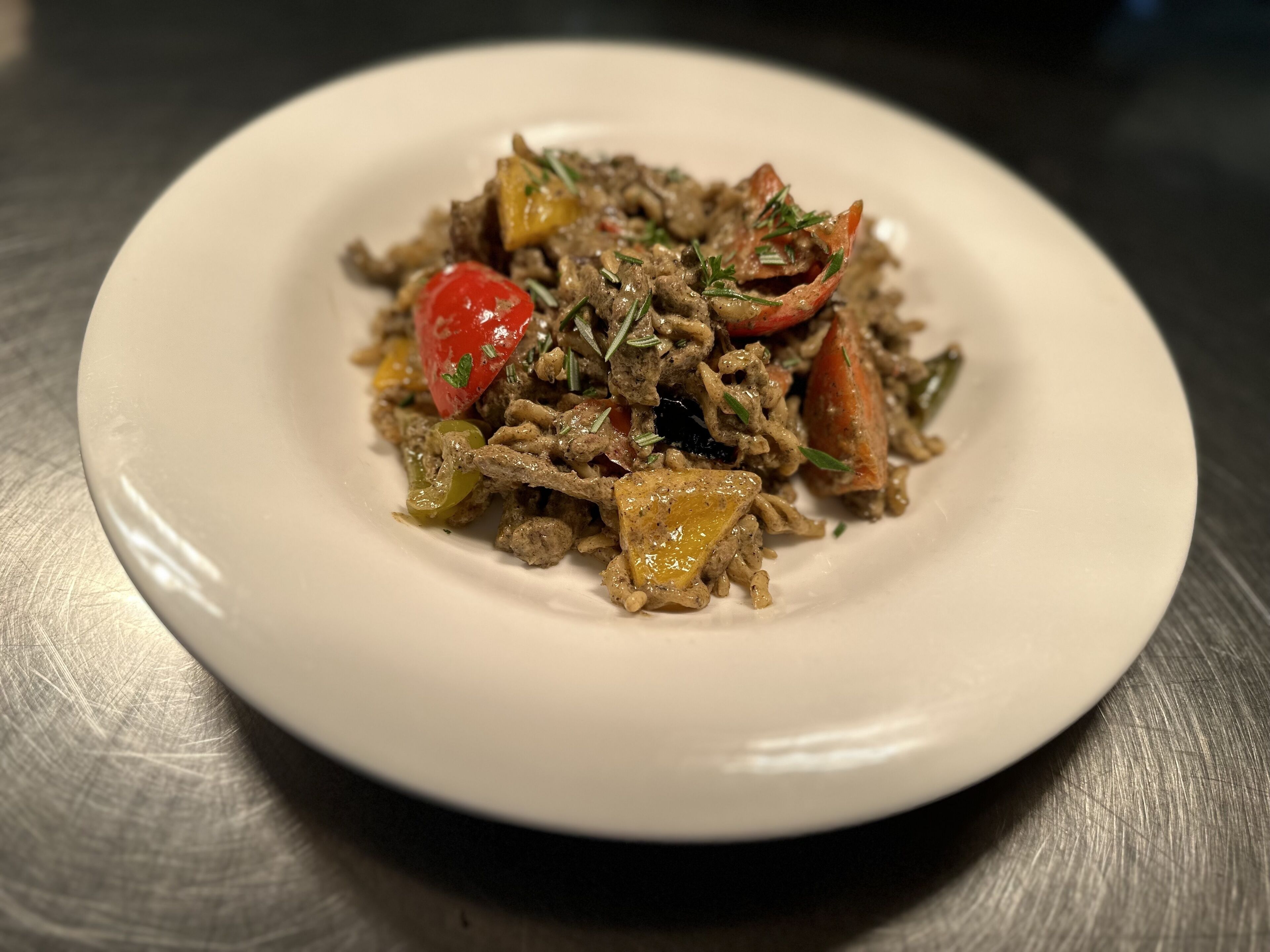 A plate of food with various vegetables and meat, served on a white plate.