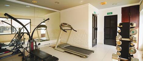 Un gimnasio con cintas de correr, elípticas y máquinas de pesas.