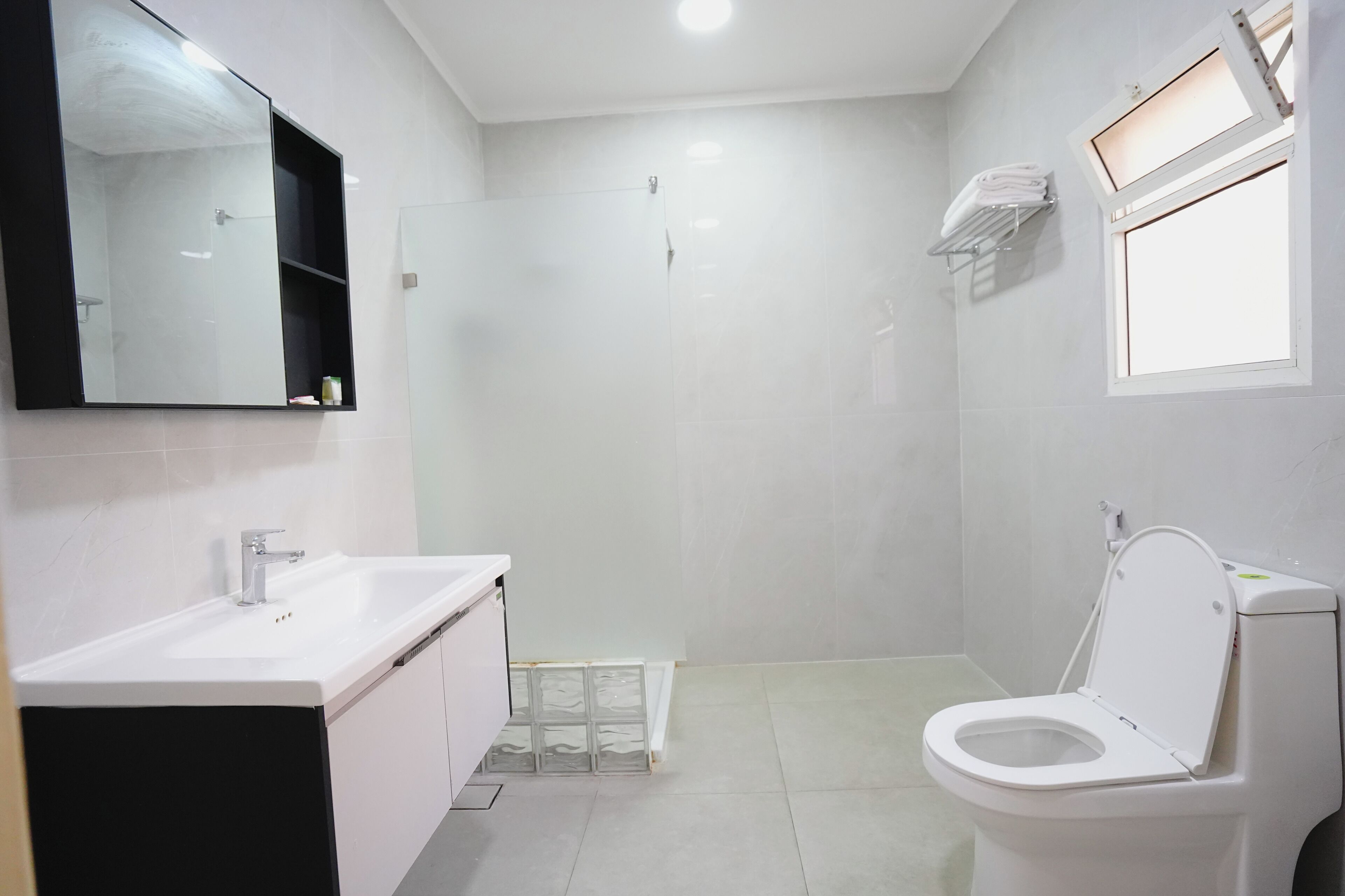 Un baño con lavamanos blanco, espejo, inodoro y ducha.