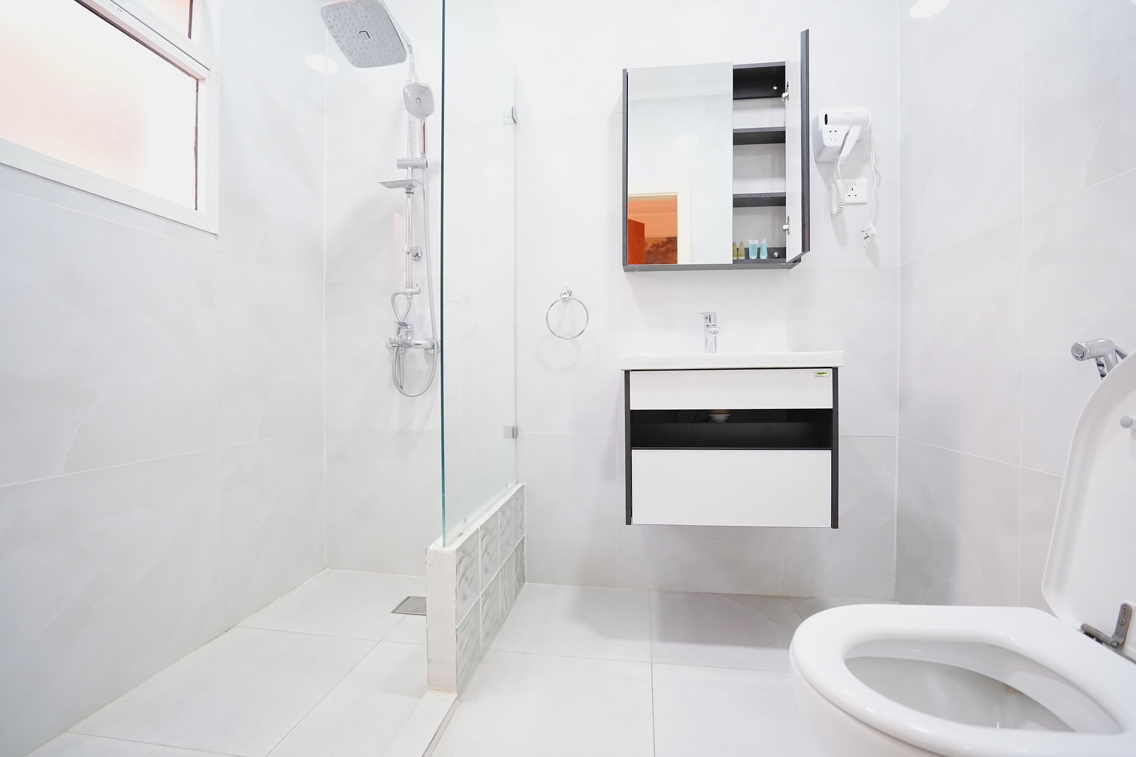 A modern bathroom with a glass-enclosed shower, a white sink with a mirror above it, and a toilet.