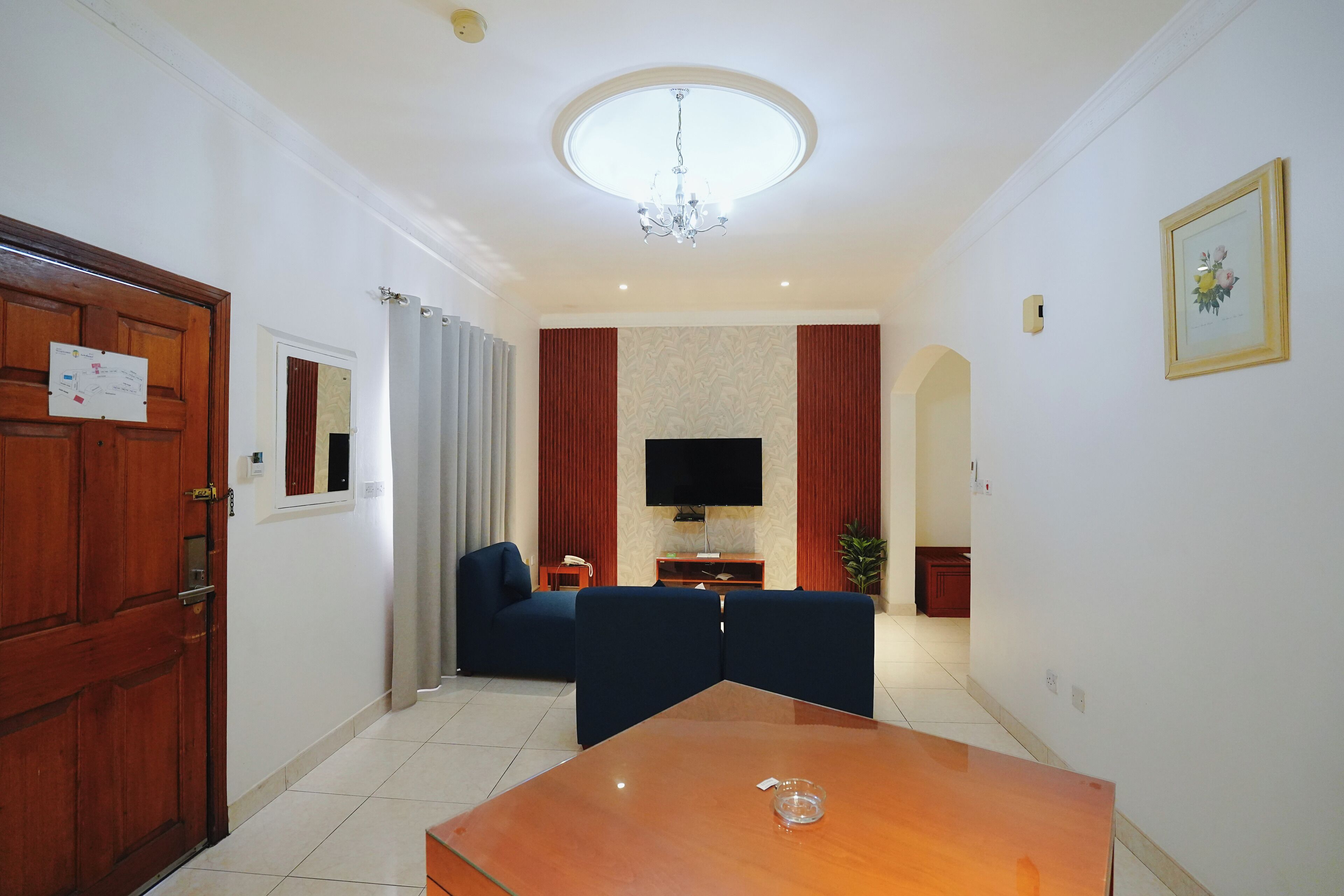 Una sala de estar con una mesa de madera, un sofá azul y un televisor.