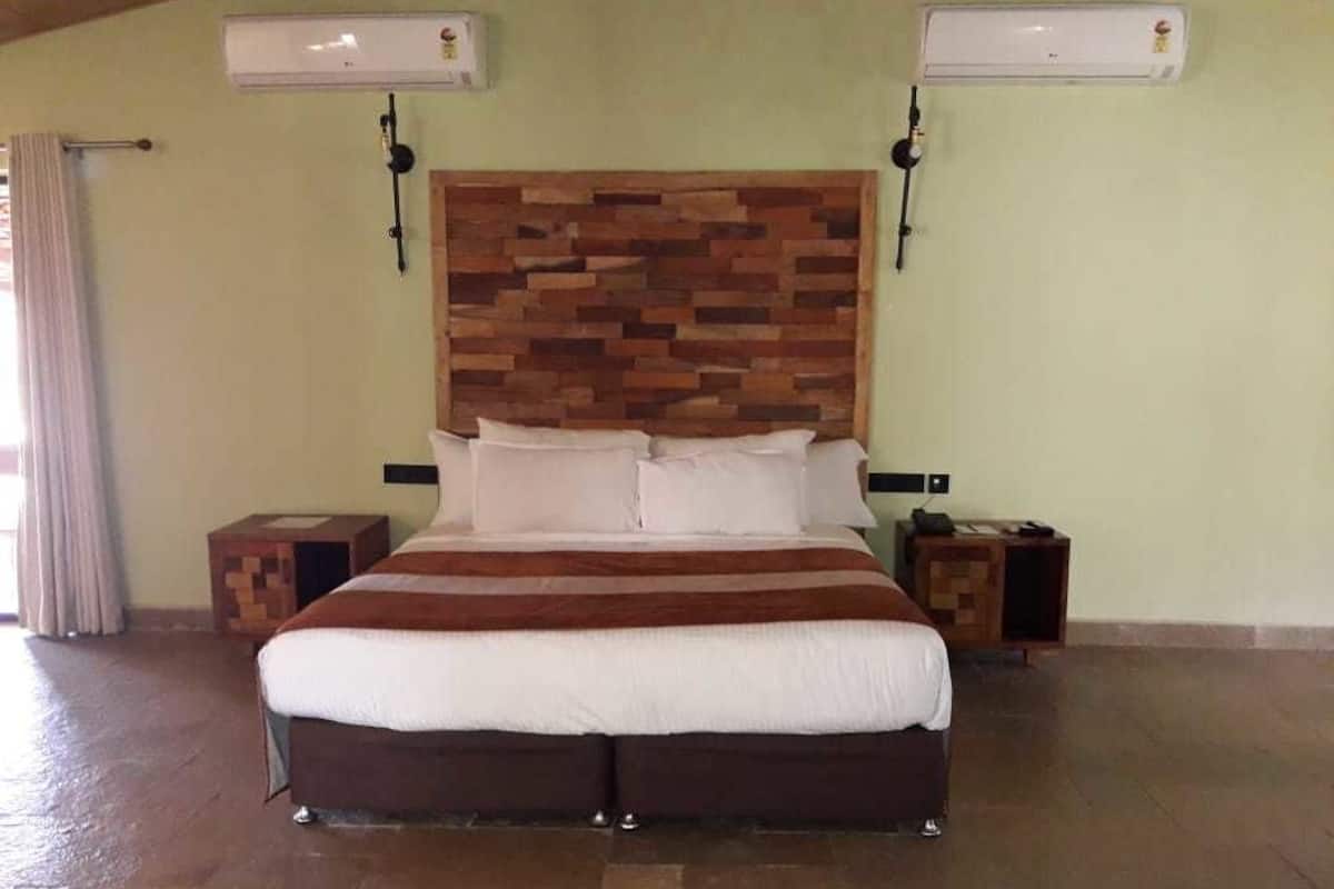 Un lit avec une tête de lit en bois, deux tables de chevet et un appareil de climatisation fixé au mur.