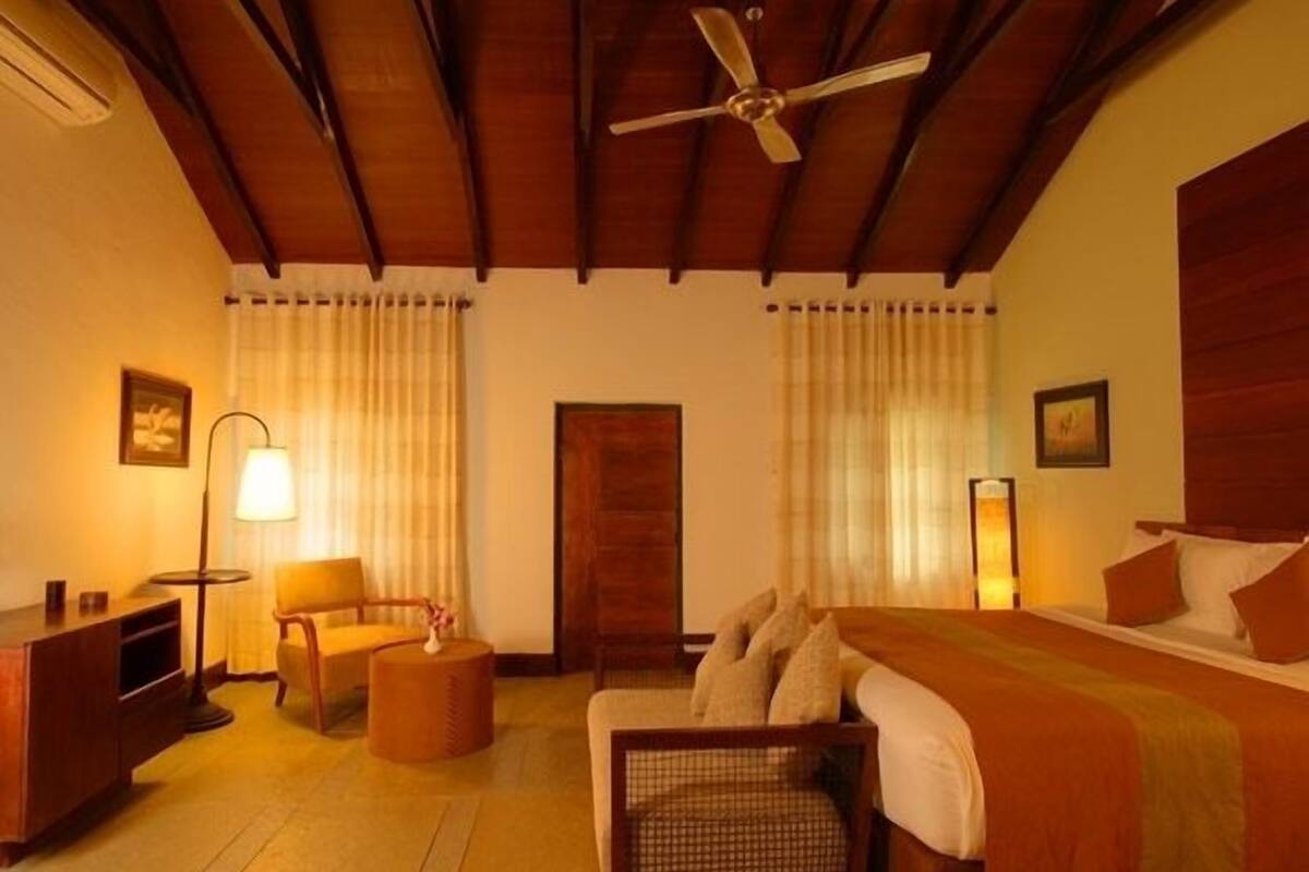 Une chambre d’hôtel avec un lit, une chaise, un bureau et un ventilateur de plafond.