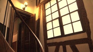 A staircase with a wooden handrail and a large window with multiple panes. - Hôtel du Lys (Paris)