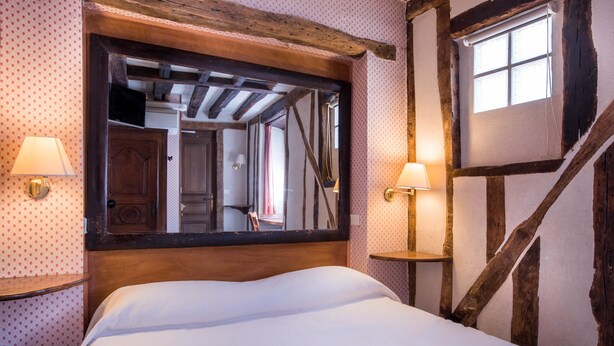 A bedroom with a large mirror, wooden beams, and two wall-mounted lamps. - Hôtel du Lys (Paris)