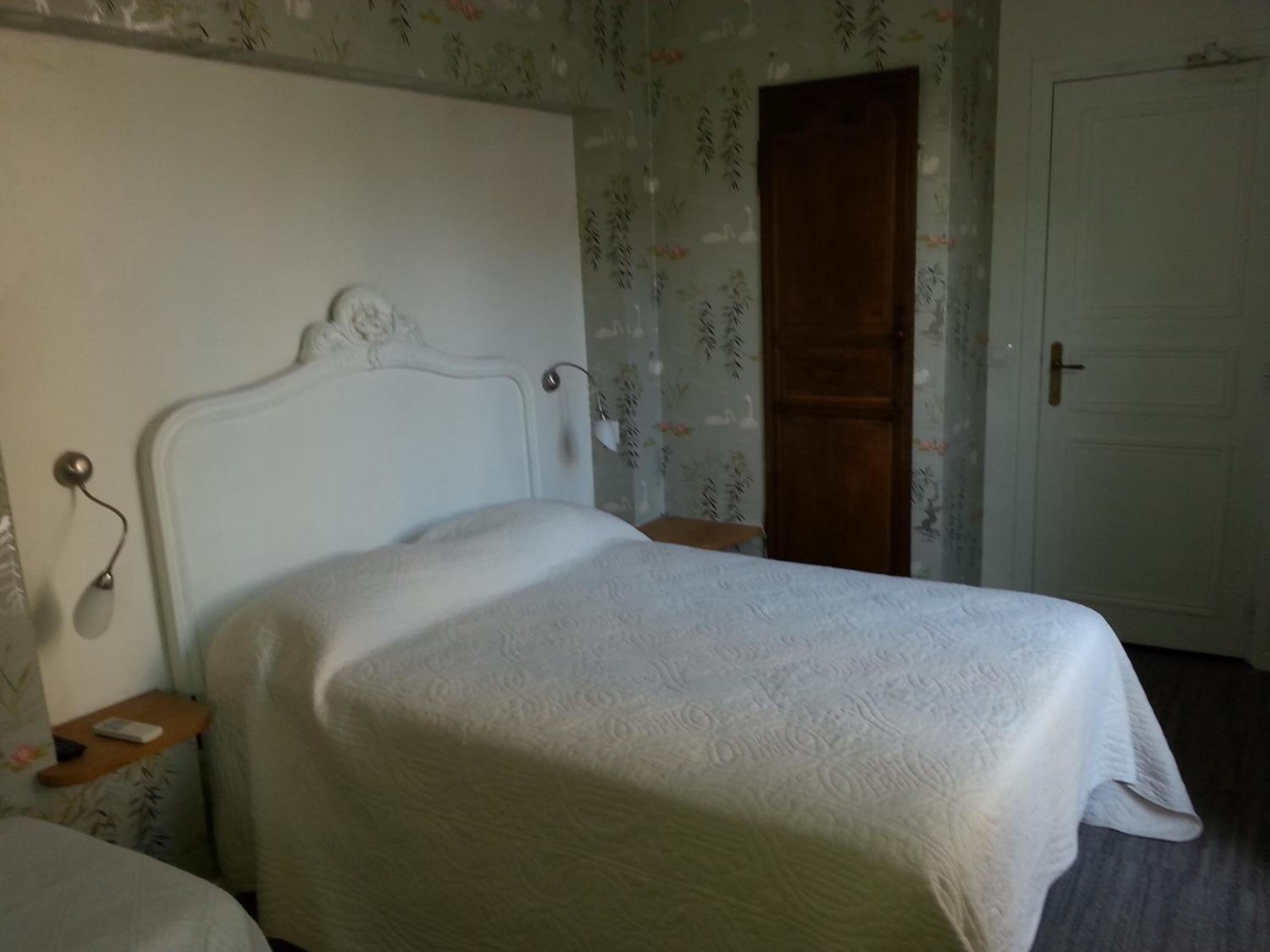 Un dormitorio con cama, mesita de noche, una puerta y papel tapiz floral.