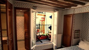 A bedroom with a bed, a window, and a balcony with a view of a red brick building. - Hôtel du Lys (Paris)
