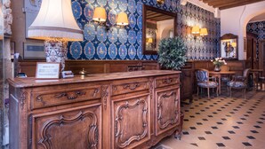 A reception area with a wooden counter, patterned wallpaper, and a mirror. - Hôtel du Lys (Paris)