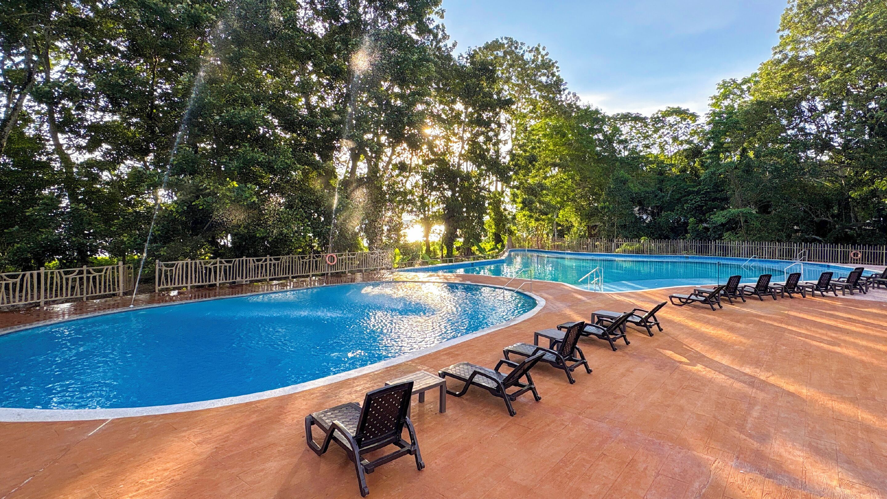 A swimming pool with a wooden deck and lounge chairs.