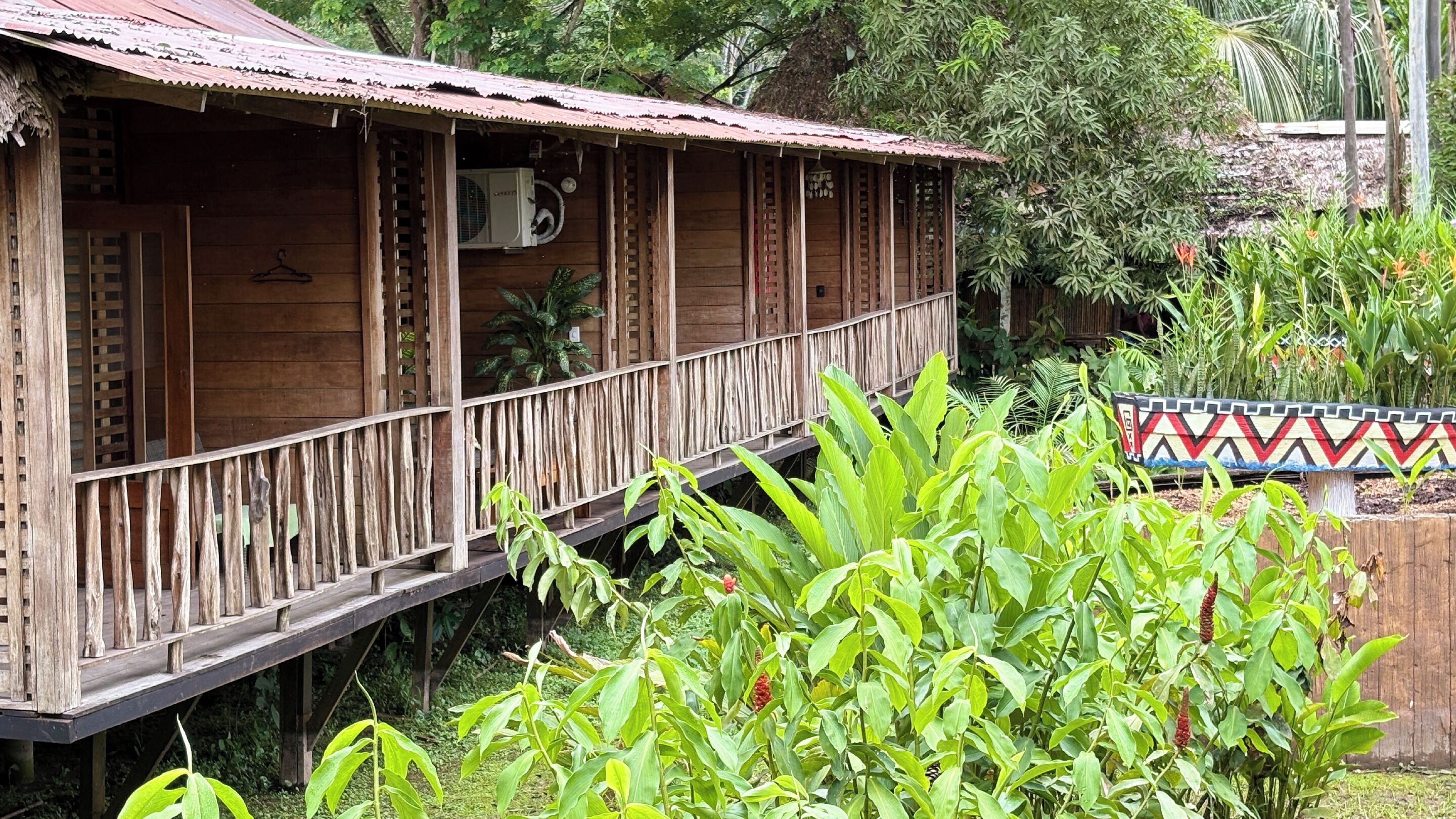 Une structure en bois dotée d’un balcon, entourée d’une végétation luxuriante.