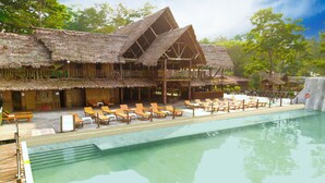 A resort with a pool, wooden deck, and thatched-roof buildings. - Hotel Amazon by On Vacation (Leticia)
