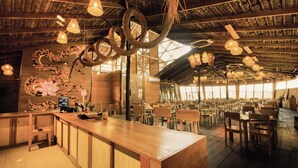 A restaurant with a wooden interior, hanging light fixtures, and a large mural on the wall. - Hotel Amazon by On Vacation (Leticia)